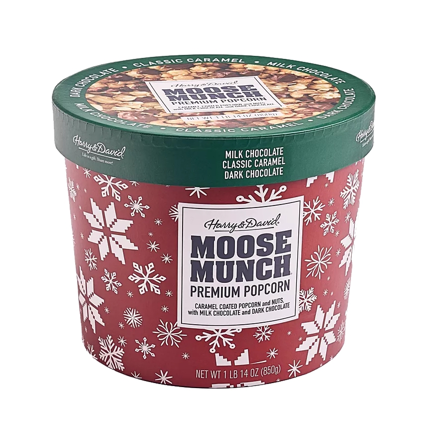 Harry & David Moose Munch Premium Popcorn is a 30oz container featuring caramel-coated popcorn and nuts, with milk chocolate and dark chocolate. The packaging is red with white snowflakes and green accents.