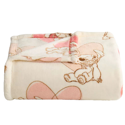 A folded fleece blanket featuring cartoon characters and pink heart designs on a light background.
