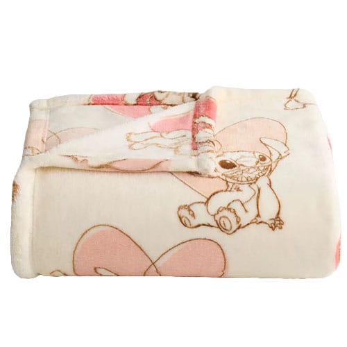 A folded fleece blanket featuring cartoon characters and pink heart designs on a light background.