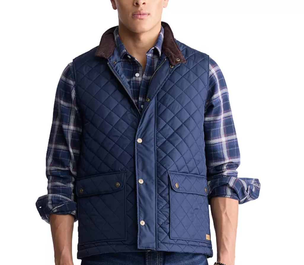 A blue quilted lightweight vest with snap buttons, flap pockets, and a dark brown collar, worn over a blue plaid shirt with rolled-up sleeves.