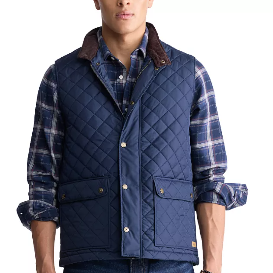 A blue quilted lightweight vest with snap buttons, flap pockets, and a dark brown collar, worn over a blue plaid shirt with rolled-up sleeves.