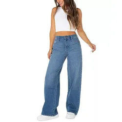A woman wearing wide-leg blue jeans and a white sleeveless crop top paired with white sneakers.