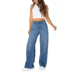 A woman wearing wide-leg blue jeans and a white sleeveless crop top paired with white sneakers.