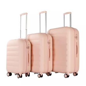A set of three pink hardside suitcases with telescopic handles and four spinner wheels each, designed for easy mobility. Each piece varies in size to accommodate different travel needs.