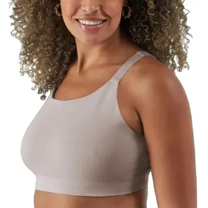 A person wearing a beige sports bra with wide straps and a racerback design.