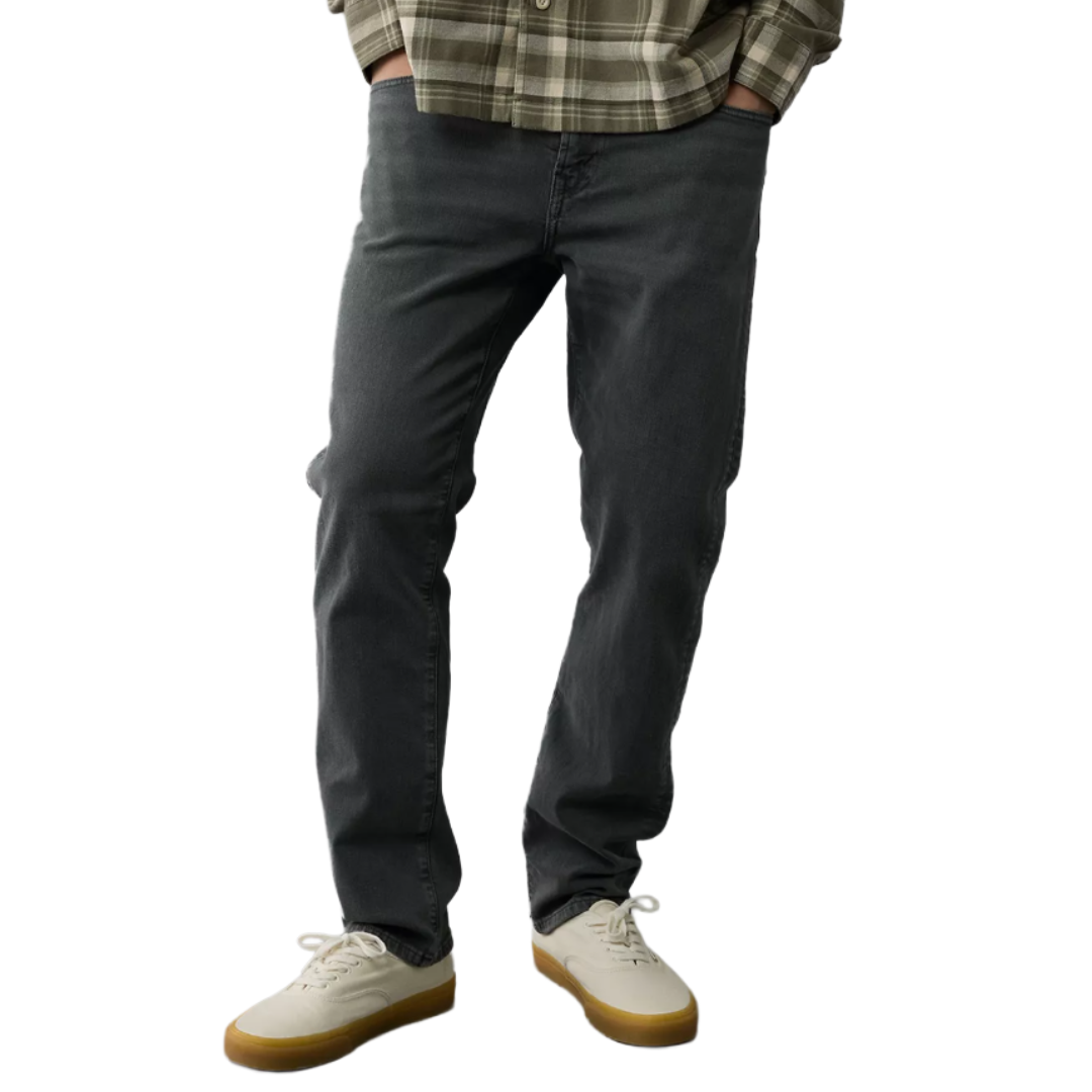 A person is wearing dark gray jeans, a plaid shirt, and off-white sneakers with gum soles.