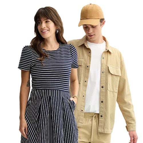 A woman wearing a navy and white striped dress stands beside a man in a beige shirt jacket, white T-shirt, jogger pants, and a beige cap.