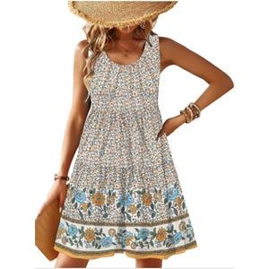Sleeveless summer dress featuring a floral print with shades of blue and orange. The skirt showcases a detailed border with larger floral patterns, paired stylishly with a straw hat, bracelets, and a clutch.