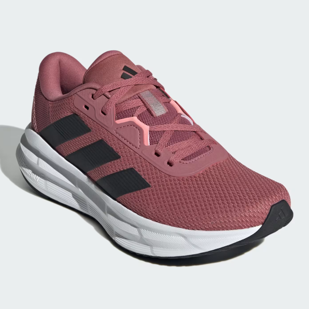 A pink sneaker with a mesh upper and black stripes on the side, featuring a white and grey sole.