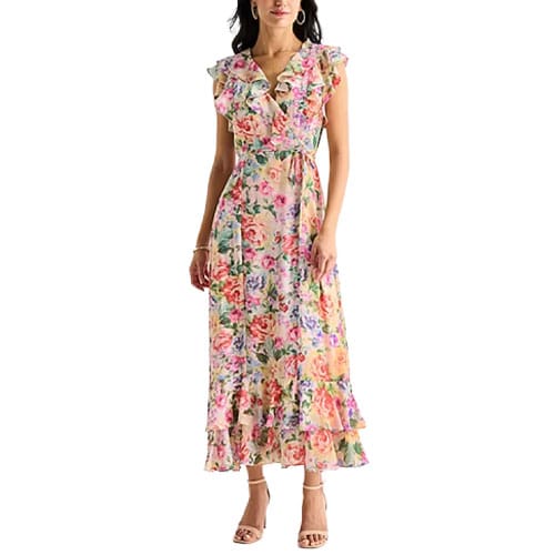 A woman is wearing a floral, sleeveless maxi dress with a ruffled V-neckline and a layered skirt. She pairs it with open-toed heels.