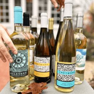 The image shows a variety of wines, including Axletree Sauvignon Blanc, Fretwork Chardonnay and Pinot Grigio from Columbia Valley, and Loudscape. Each bottle has distinct labels, with prominent use of blue, white, and black color schemes.