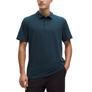 A man wears a dark teal short-sleeve polo shirt with a buttoned collar, paired with dark pants.