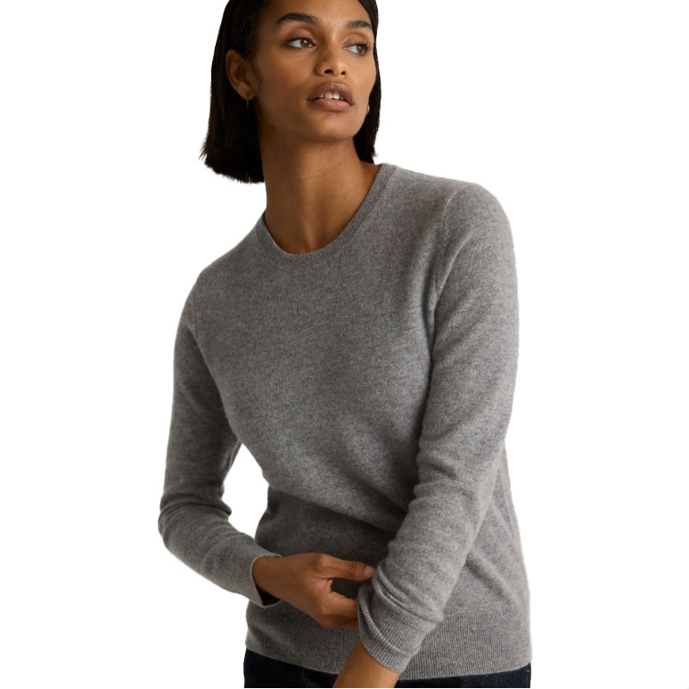 A woman wearing a classic crew neck sweater in gray.