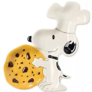Ceramic dish in the shape of a cartoon dog wearing a chef's hat, holding a large, yellow cookie with chocolate chips.