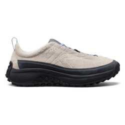 A beige sneaker with a textured upper, black sole, and blue accents. It features a rugged, traction-oriented outsole for outdoor activities.