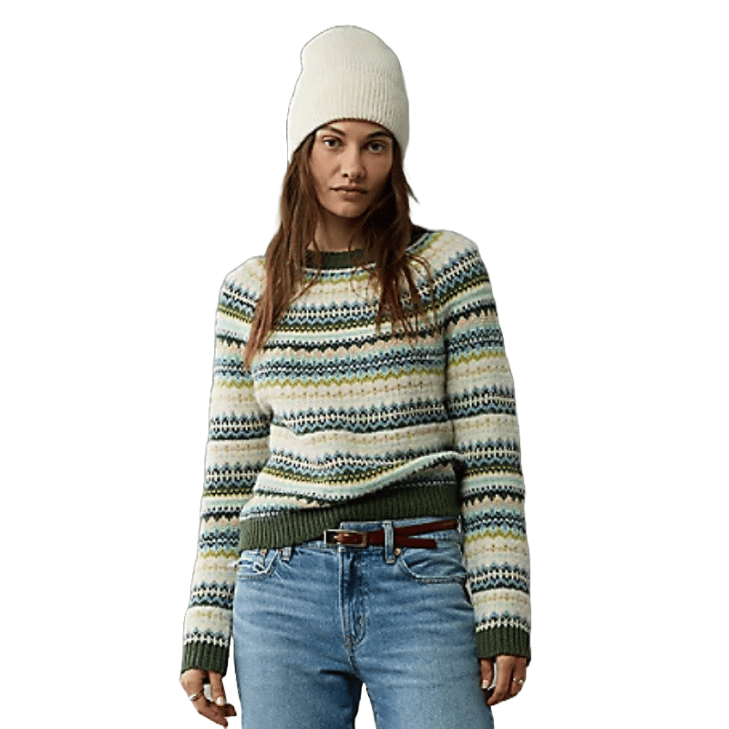 A woman is wearing a crewneck sweater with horizontal stripes in muted colors and patterns, paired with light wash jeans and a beanie.