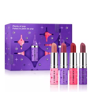 Four Clinique lipsticks are displayed in front of a purple box with star patterns. The packaging reads \“Plenty of pop.\“