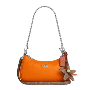 Orange Coach handbag with a silver chain strap, brown trim, and star-shaped leather charm.