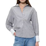A woman is wearing a black and white striped button-up shirt with a white collar and cuffs, paired with blue jeans.