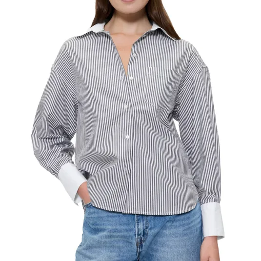 A woman is wearing a black and white striped button-up shirt with a white collar and cuffs, paired with blue jeans.