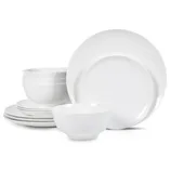 A set of white dinnerware includes plates and bowls stacked together, showcasing a simple and elegant design.