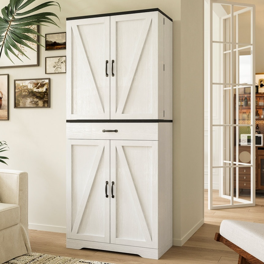 A stylish living room features a white barn-style cabinet, complemented by a beige sofa, a textured rug, and a coffee table with apples. Wall art and a plant add decorative elements, and a glimpse into a kitchen with open shelving is visible through the doorway.