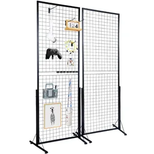 2-pack VEVOR Grid Wall Panels, each with a black metal wireframe design, featuring a variety of hanging items such as a light bulb, game controller, clipboard, and picture frame. Panels are freestanding with sturdy metal bases.