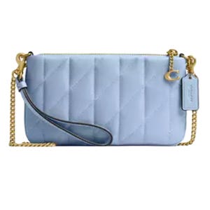 A light blue quilted handbag with a gold chain shoulder strap and a detachable wrist strap. It features a gold-tone clasp and an attached tag.
