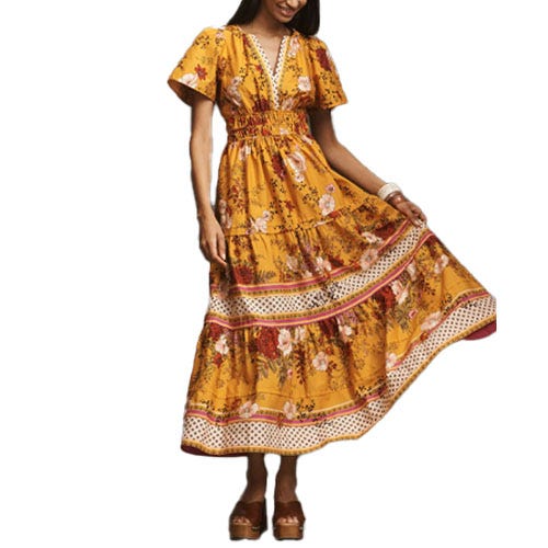 A woman wears a yellow floral bohemian-style maxi dress with short sleeves, a v-neck, and tiered skirt details.
