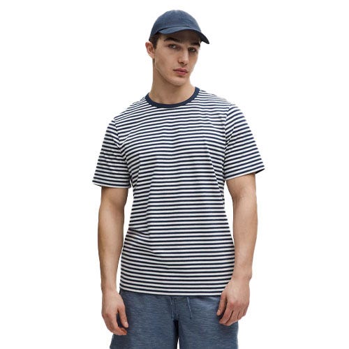 A man is wearing a navy and white striped T-shirt, blue shorts, and a navy baseball cap.