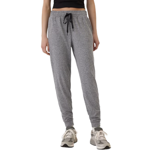 A person is wearing gray jogger sweatpants with an elastic waistband and black drawstring, paired with gray and white sneakers.
