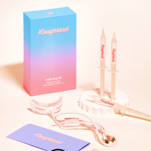 Laughland whitening kit includes syringes, a mouth tray with LED light, cables, and an instruction card. The packaging is blue and pink.