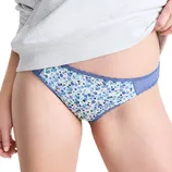 Blue floral lace-trimmed panties worn by a person, partially covered by a light gray top.
