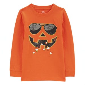 An orange long-sleeved tee featuring a black graphic of a pumpkin wearing sunglasses, designed with a glow-in-the-dark effect.
