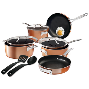 Copper-colored cookware set with lids includes a frying pan, a saucepan with a lid, a deep pot with a lid, and kitchen utensils like a spatula and a spoon. There's a fried egg cooking in one of the pans.