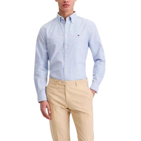 A man is wearing a light blue checkered button-up shirt and beige dress pants, paired with brown loafers.