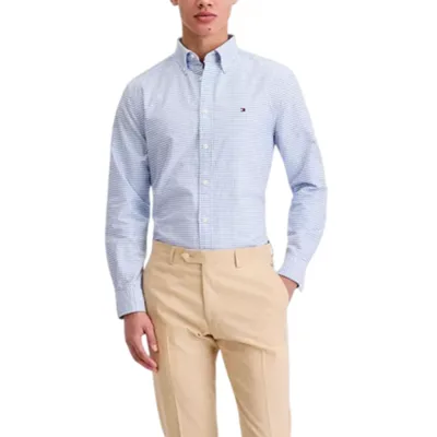 A man is wearing a light blue checkered button-up shirt and beige dress pants, paired with brown loafers.