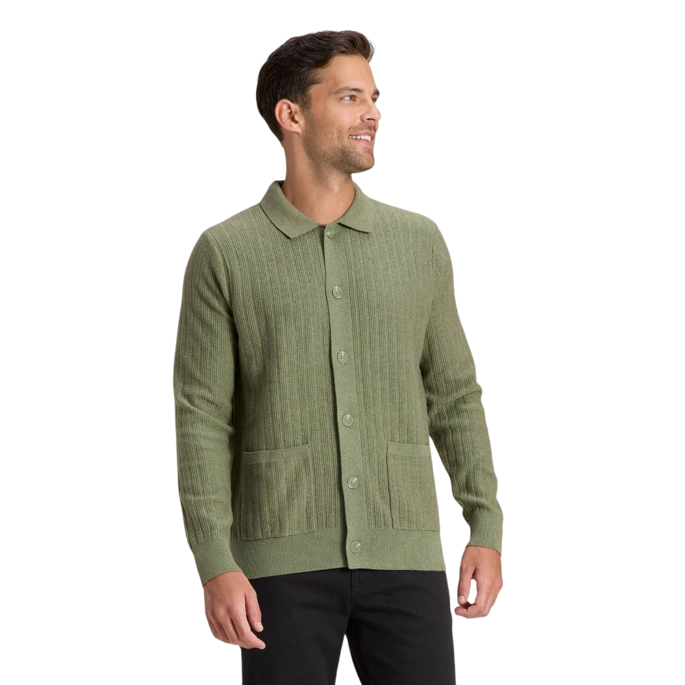 A man is wearing a light green, ribbed cardigan with a button-up front and two pockets, paired with black pants.
