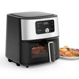 Cuisinart air fryer with a digital display and control knob, showing food being cooked inside. A plate with cooked salmon and vegetables is visible next to it.