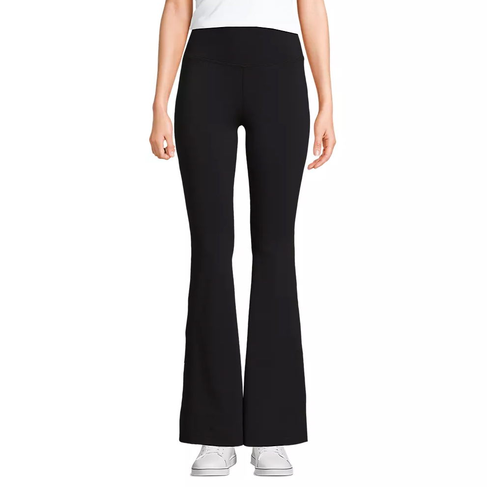 Black flared yoga pants paired with white sneakers, worn by a person standing against a plain background.