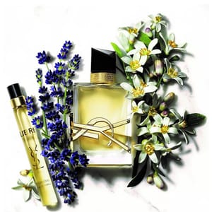 A bottle of Yves Saint Laurent perfume flanked by a tube of concentrate and various flowers.