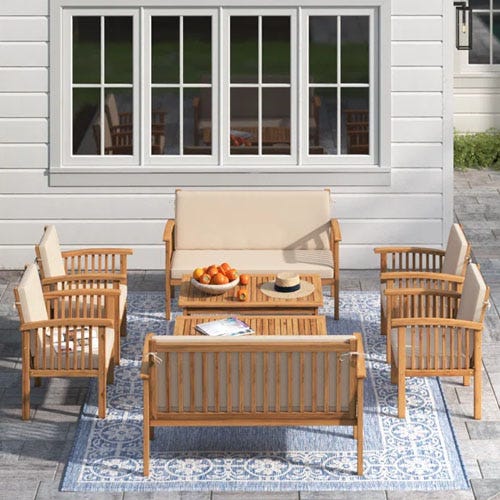 A wooden patio set with two tables, two loveseats, and four arm chairs.