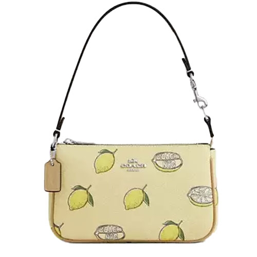 A small Coach shoulder bag with a lemon print on a light background, featuring a detachable leather strap and metal hardware accents.