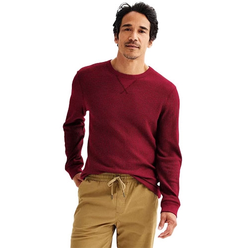 A man is wearing a red long-sleeve shirt and tan drawstring pants.