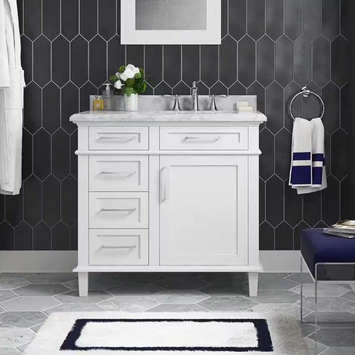 A white bathroom vanity with a marble countertop and chrome faucets, paired with a dark geometric-patterned wall, a mirror, and navy and white bathroom accessories.