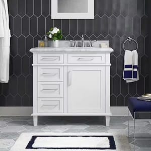 A white bathroom vanity with a marble countertop and chrome faucets, paired with a dark geometric-patterned wall, a mirror, and navy and white bathroom accessories.