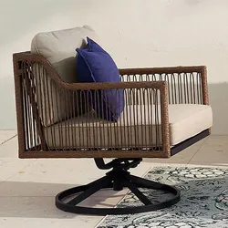 A swivel outdoor armchair with wicker sides, beige cushions, and a blue throw pillow.