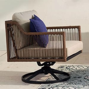 A swivel outdoor armchair with wicker sides, beige cushions, and a blue throw pillow.