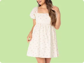 A light-colored, floral-patterned short dress features puff sleeves and a square neckline against a green background.