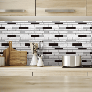 Modern kitchen features a black and white mosaic tile backsplash with wooden cabinets. A stainless steel pot, wooden cutting boards, whisks, and a potted plant are on the countertop.